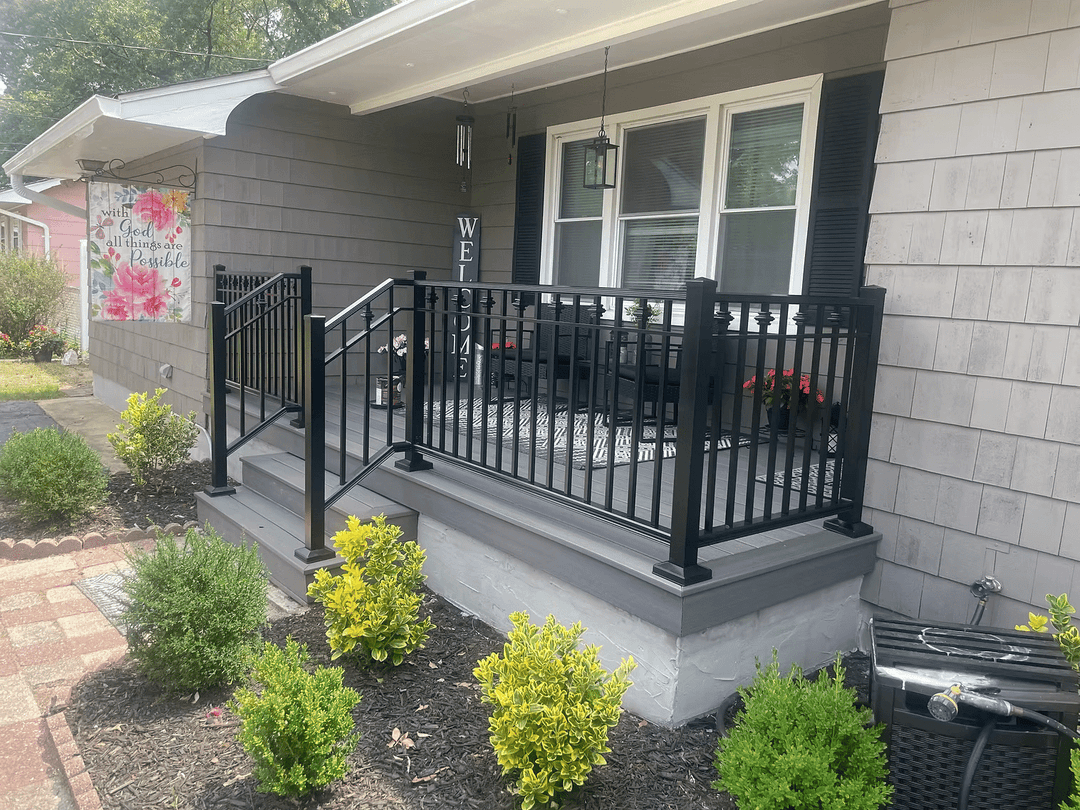 Black railing on a porch with flower planters and decorative welcome sign, enhancing outdoor appeal.