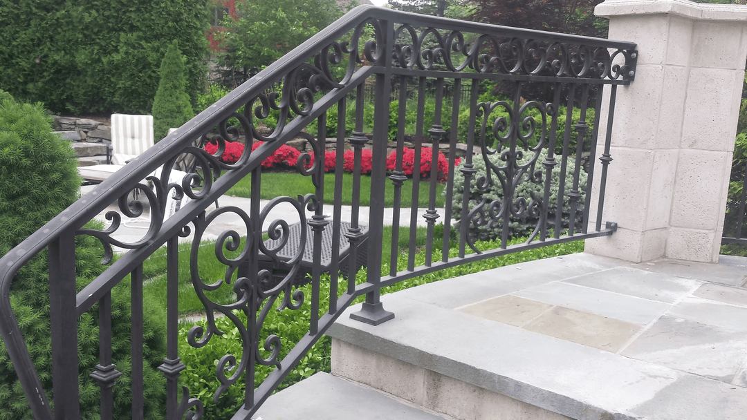 Elegant wrought iron railing with intricate designs, complementing a lush landscaped garden.
