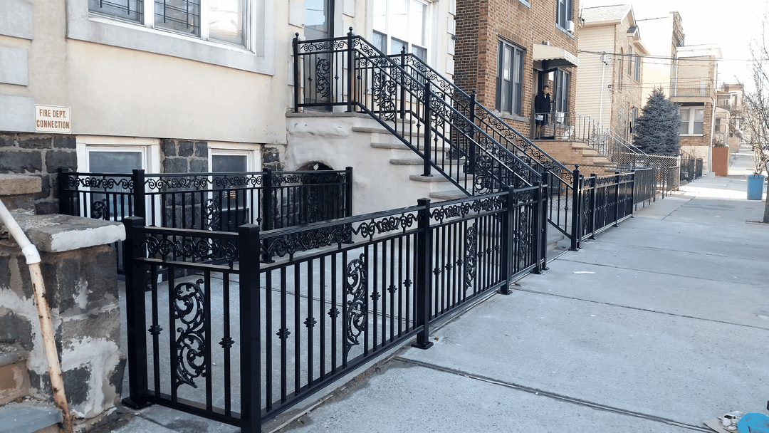 Decorative black iron fence and railing outside a residential building on a city street.
