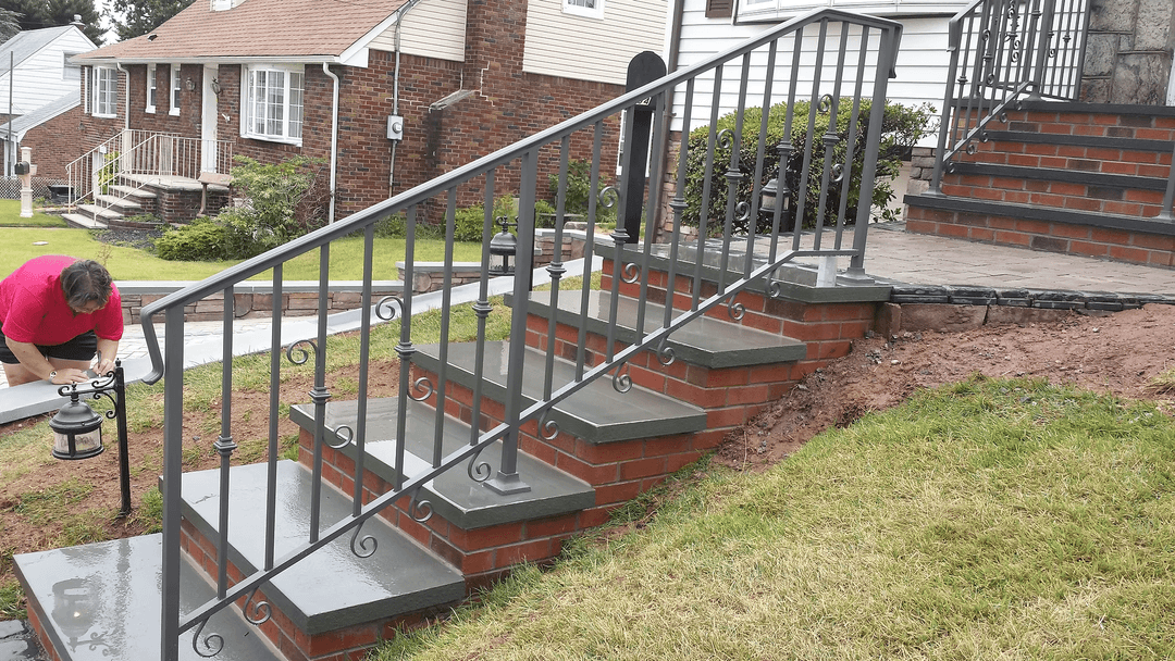 Newly installed brick stairs with decorative metal railing and landscaping elements.